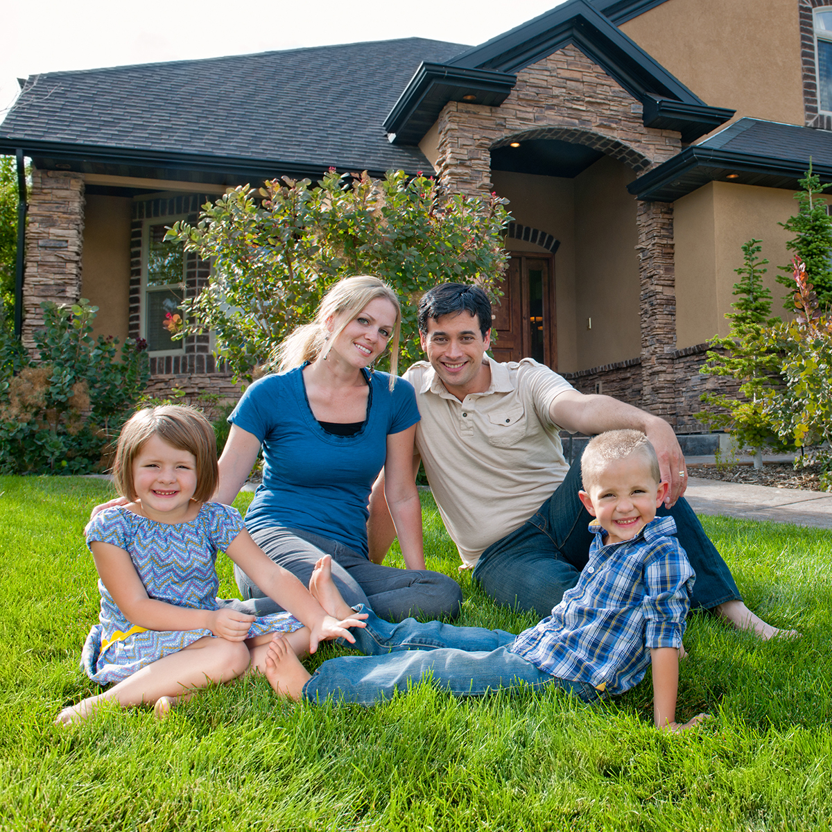 Smiling family on front lawn of a house